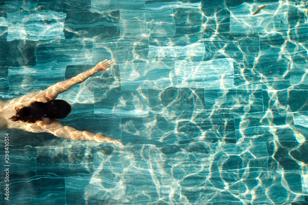 Top view of  man swimming in the clear blue water of a swimming pool