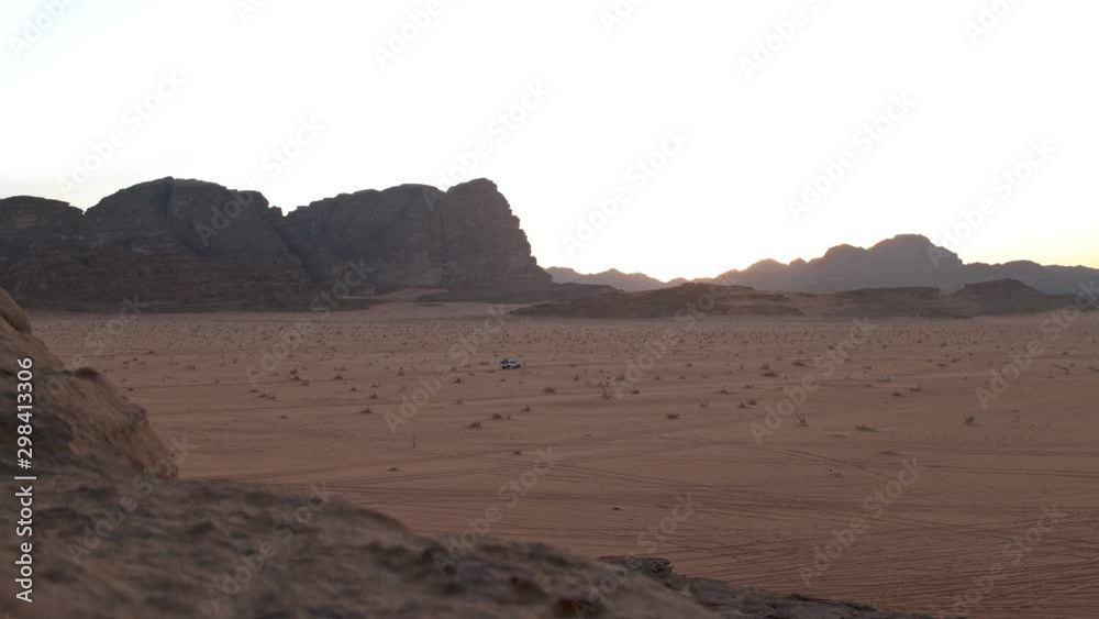 A beautiful landscape in the desert of Jordan, the sand has a reddish color, like on Mars, a car rides in the frame and the mountains are visible A beautiful landscape in the desert of Jordan, the sand has a reddish color, like on Mars, a car rides in the frame and the mountains are visible