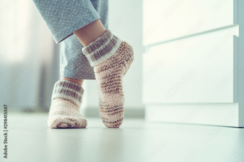 Woman in pajamas and cozy soft warm knitted winter socks at home - obrazy, fototapety, plakaty 