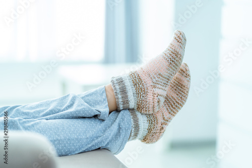 Woman resting on the sofa in pajamas and cozy soft warm knitted winter socks at home