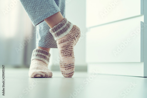 Woman in pajamas and cozy soft warm knitted winter socks at home