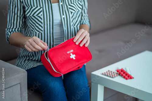 A woman holds a medical first aid kit with medicine at home