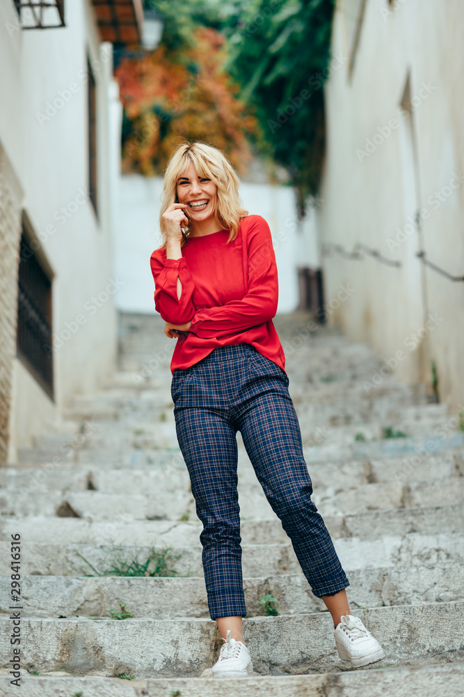 Happy young blond woman laughing on beautiful steps in the street.