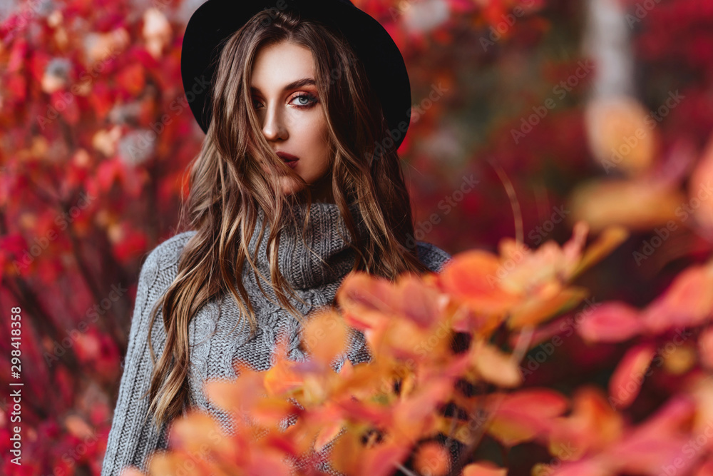 Fashion woman on a background of red and yellow autumn leaves - obrazy, fototapety, plakaty 