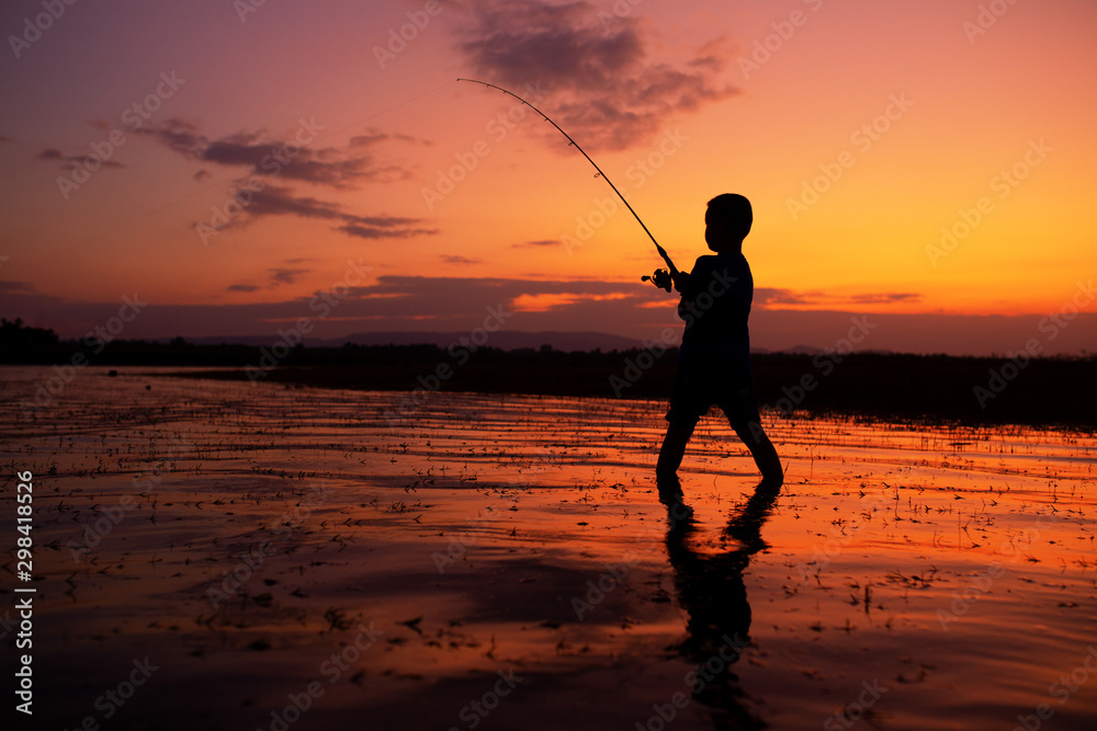 A boy fishing at the lake during silhouette sunset lifestyles of child