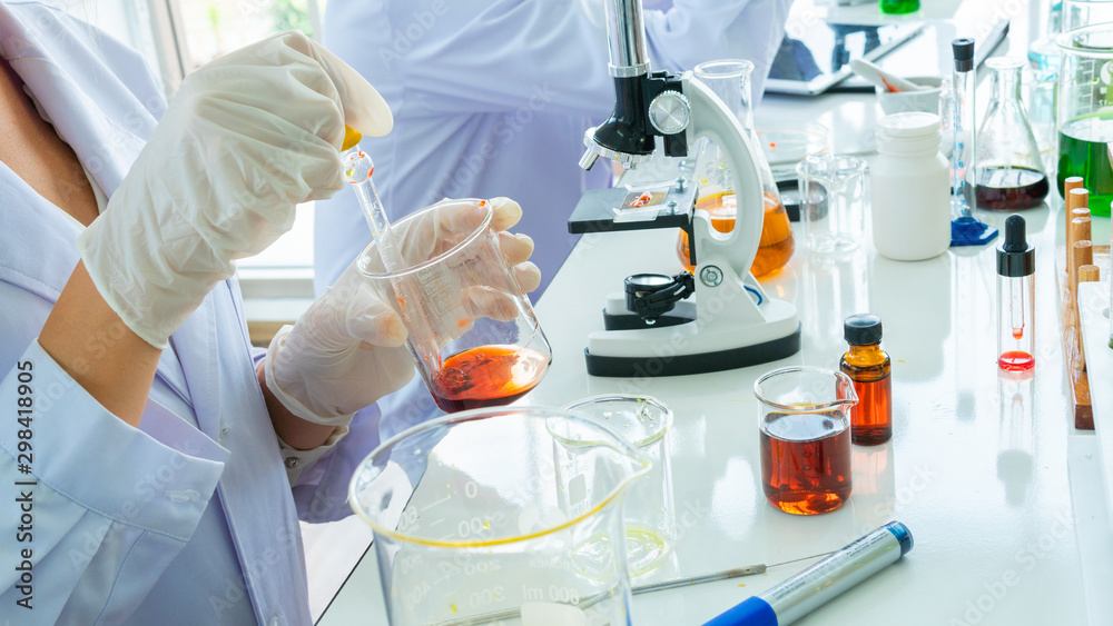 close up scientist’s hand with tube and beaker and microscope. With