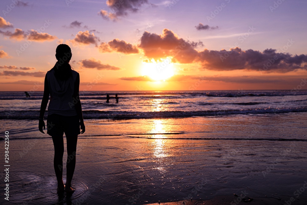 Fototapeta premium Siluette of a human on the beach holding a flag