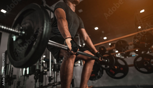 Εκτύπωση καμβά A side view of a young bodybuilder exercising in the gym, ready to lift weights, lift weights, work out all leg muscles and parts of the body