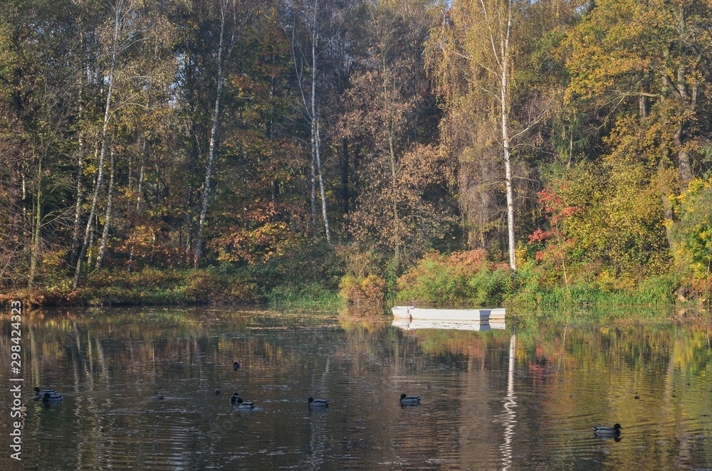 Beautiful autumn colorful landscape. Boat in a pond in a city park among colorful trees. Beautiful autumn colorful landscape. Boat in a pond in a city park among colorful trees.