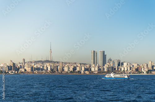 A pleasure ship floats against the backdrop of skyscrapers and residential buildings of the Asian side of Istanbul. One can see a high well-recognizable television tower.