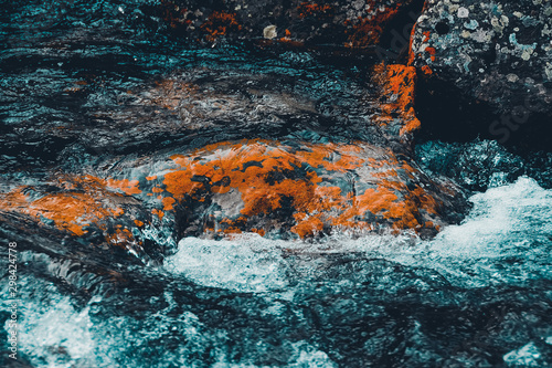 Strong mountain river. Rapid flow of stream among rocks. Blue stream of water seethes in rocks