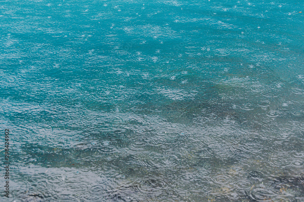 Raindrops on water surface of lake. The turquoise water of river. Rainy weather at sea Raindrops on water surface of lake. The turquoise water of river. Rainy weather at sea