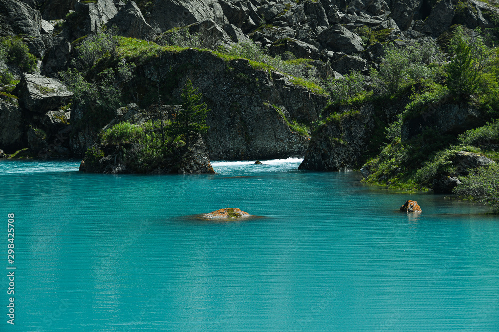 Rock on shore of blue sea. Turquoise mountain lake, the surface of river