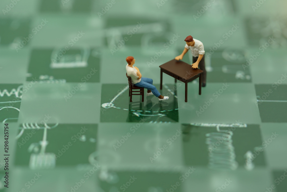 Miniature people sitting with table on Green chess board. Miniature people sitting with table on Green chess board.