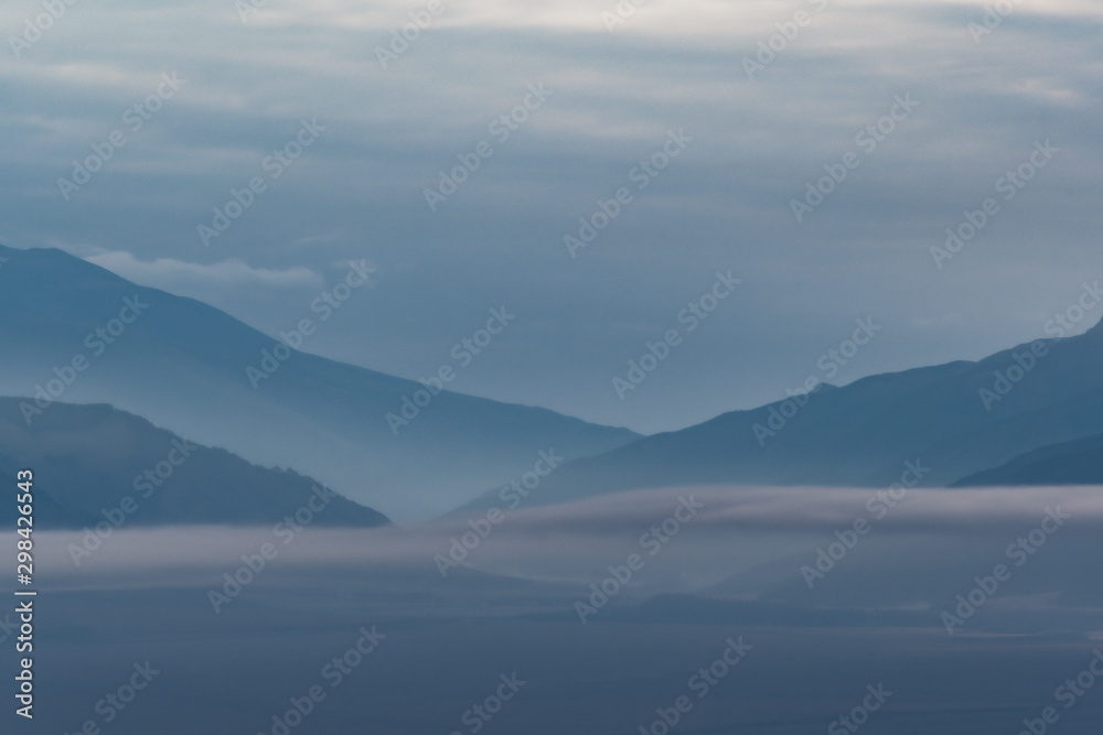 Gentle hills in bluish haze. Soft light in early morning, silhouettes of mountains