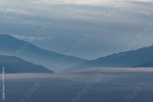 Gentle hills in bluish haze. Soft light in early morning, silhouettes of mountains © Koirill