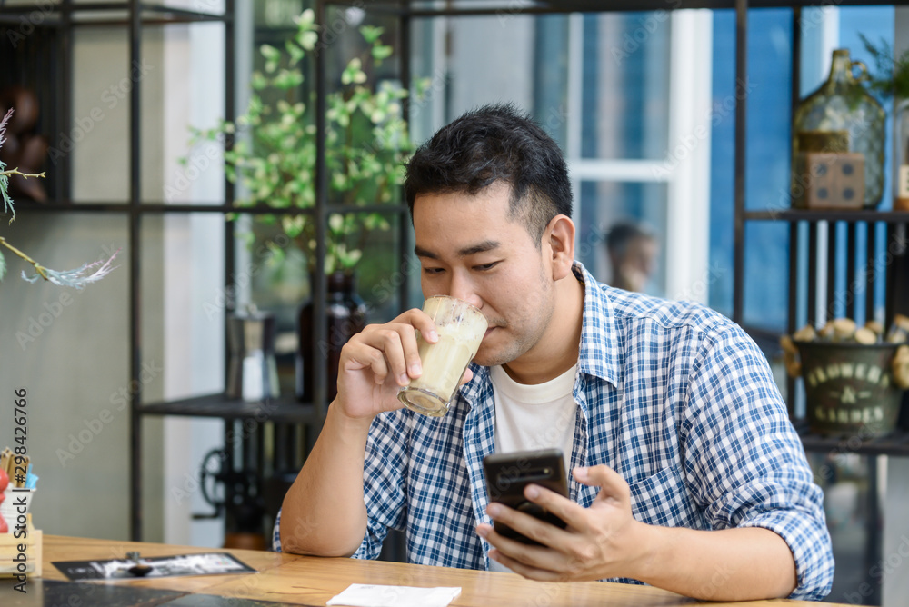 Smart Asian man using smartphone in cafe and drinking coffee, lifestyle concept. Smart Asian man using smartphone in cafe and drinking coffee, lifestyle concept.