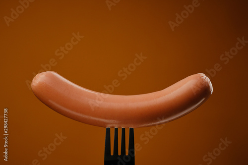 sausage on a fork isolated. brown background
