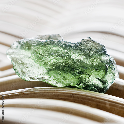 Macro photography of a moldavite stone on a wicker background