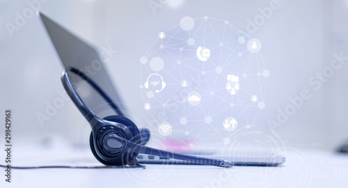 close up headset of call center and VOIP communication with futuristic virtual icon telecommunication technology on office table  in monitoring room for network operation job concept