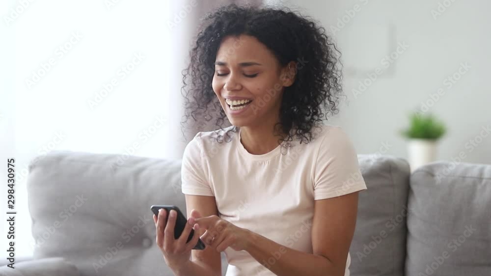 Laughing african woman holding smartphone read anecdote feels overjoyed Laughing african woman holding smartphone read anecdote feels overjoyed