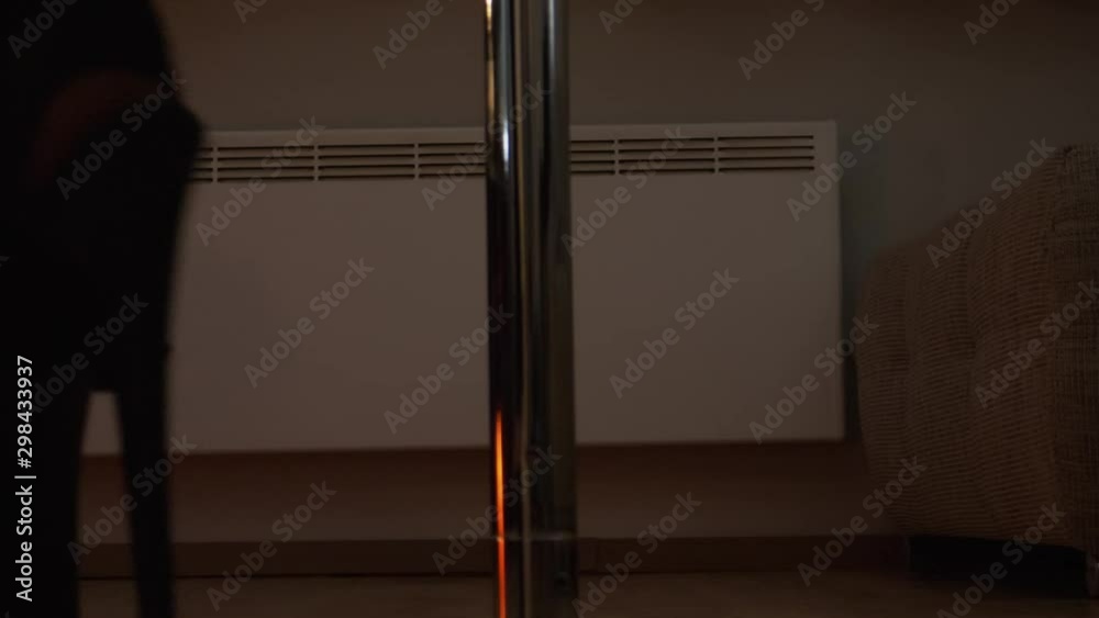 Athletic woman pole dancing in her living room; wearing extremely high heels; slow pan up; close up. Athletic woman pole dancing in her living room; wearing extremely high heels; slow pan up; close up.