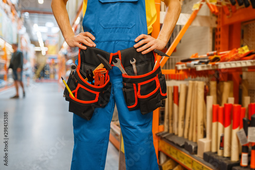 Male builder trying on tool belt in hardware store