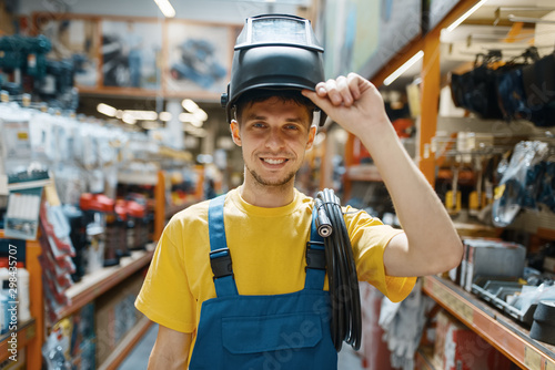 Builder choosing welding helmet in hardware store photo