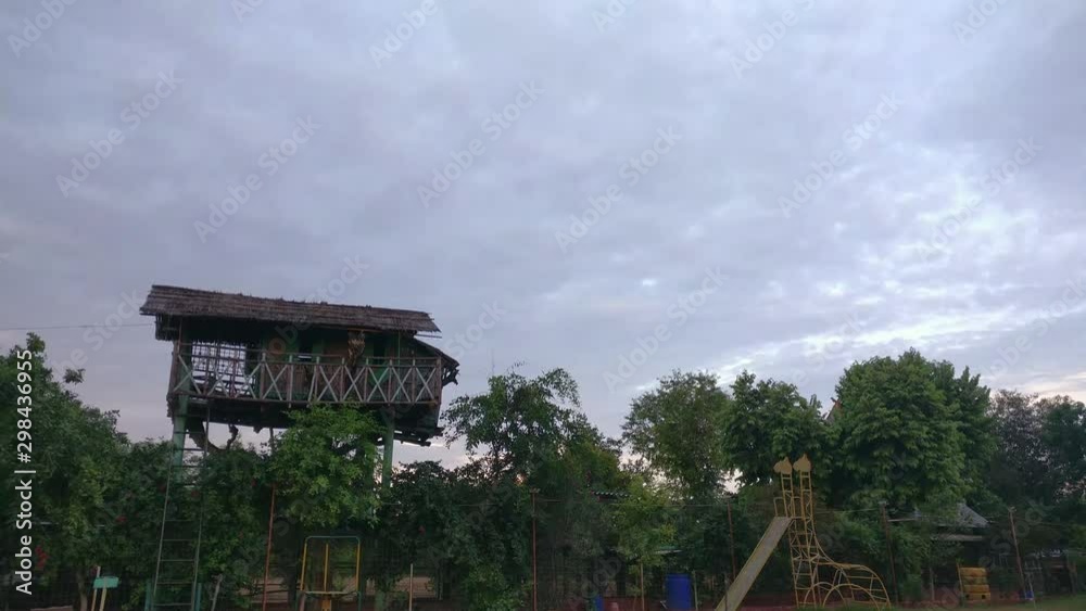 Panning up establishing shot of a garden with swings and a tree house on a cloudy day, a popular sight in the new resorts in Rajasthan Panning up establishing shot of a garden with swings and a tree house on a cloudy day, a popular sight in the new resorts in Rajasthan
