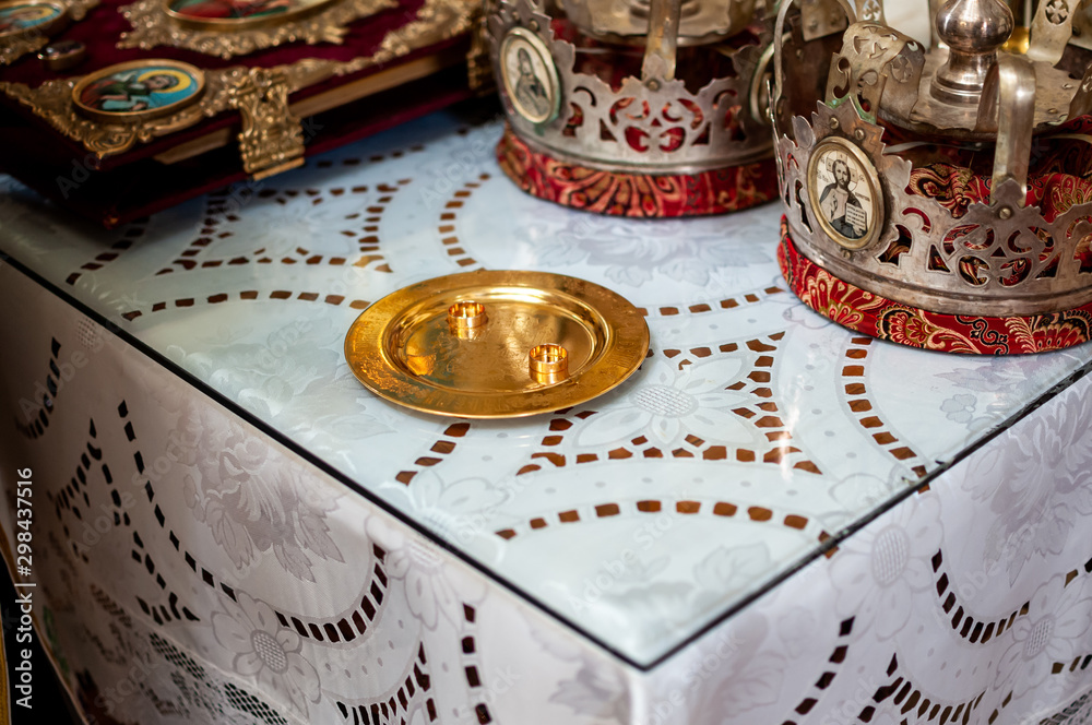 Fototapeta premium Gold wedding rings on the gold plate in the church