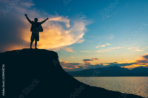 silhouette of man on mountain top over sky and sun light background,business, success, leadership, achievement and people concept