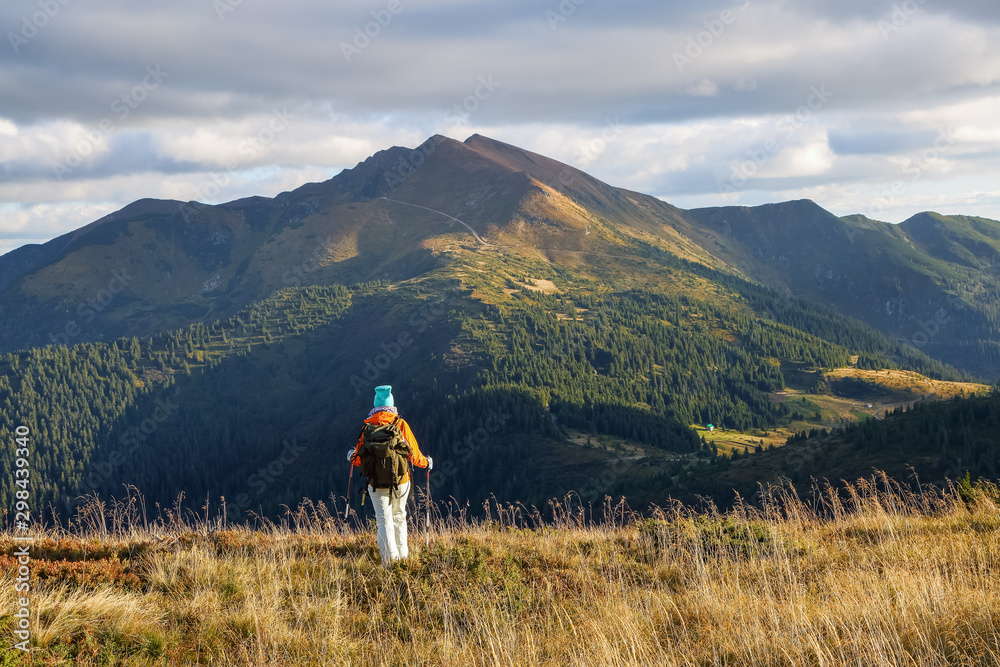 Scenery autumn sunny day. There is a tourist standing in sport clothes watching the mountains peak, sky with clouds. Scenery autumn sunny day. There is a tourist standing in sport clothes watching the mountains peak, sky with clouds.