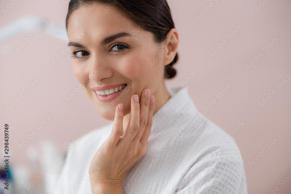 Joyful young woman touching her face with perfect skin Joyful young woman touching her face with perfect skin