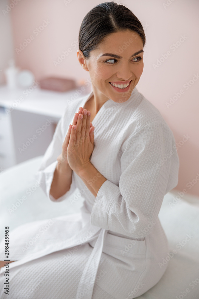 Cheerful young woman sitting on daybed at beauty salon Cheerful young woman sitting on daybed at beauty salon