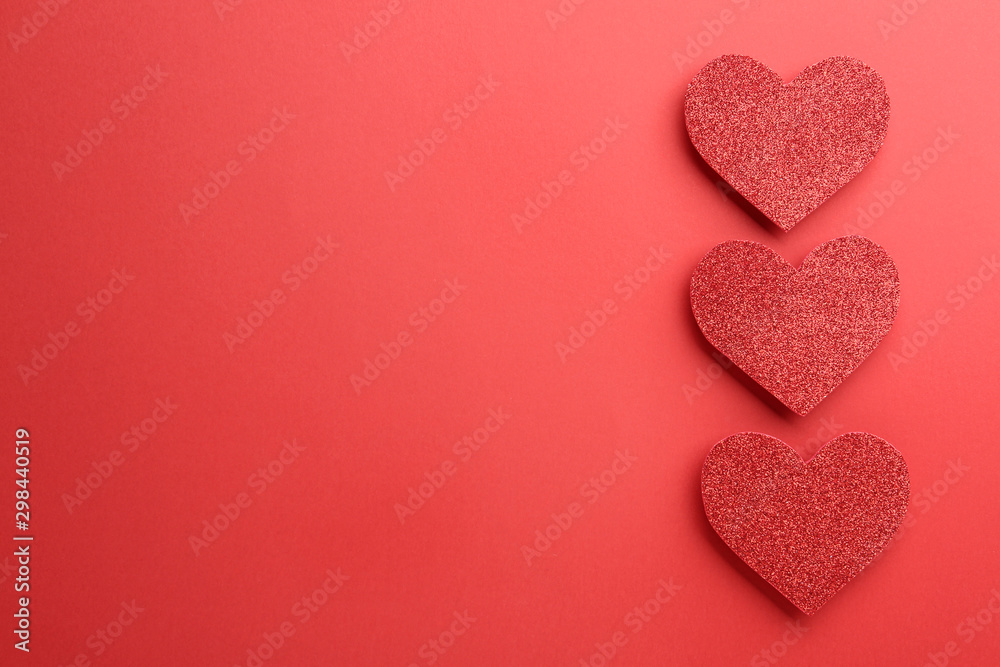 Shiny paper hearts on red background, flat lay. Space for text