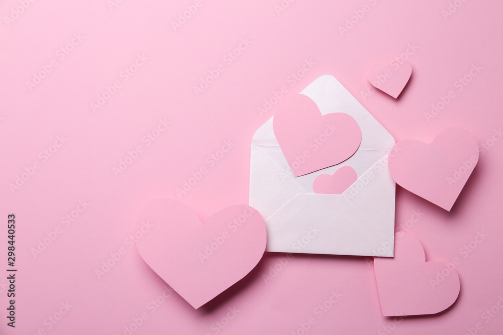 Paper hearts and envelope on pink background, flat lay