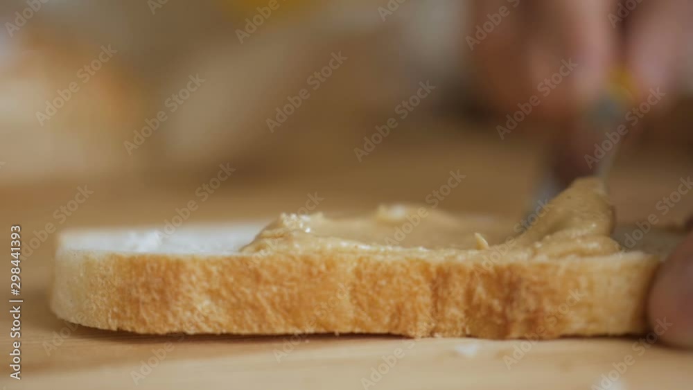 Delicious and hearty breakfast nut cream on a crisp bread. Man makes a peanut butter sandwich.. Closeup of male hands spreading butter on bread in kitchen, slow motion. Delicious and hearty breakfast nut cream on a crisp bread. Man makes a peanut butter sandwich.. Closeup of male hands spreading butter on bread in kitchen, slow motion.