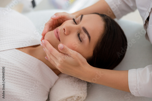 Masseuse massaging lady face at beauty salon