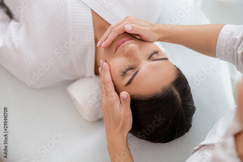 Relaxed young woman having face massage at beauty salon