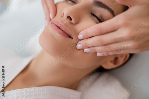 Young lady having face massage at spa salon