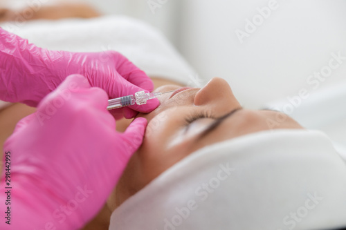 Beautician hands making injection in lady lips