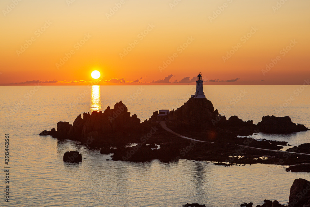 Corbiere Lighthouse on the island of Jersey, silhouetted against a sunset sky
