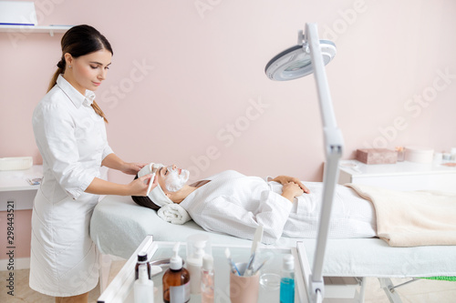 Φωτογραφία Beautician applying cosmetic mask on young woman face