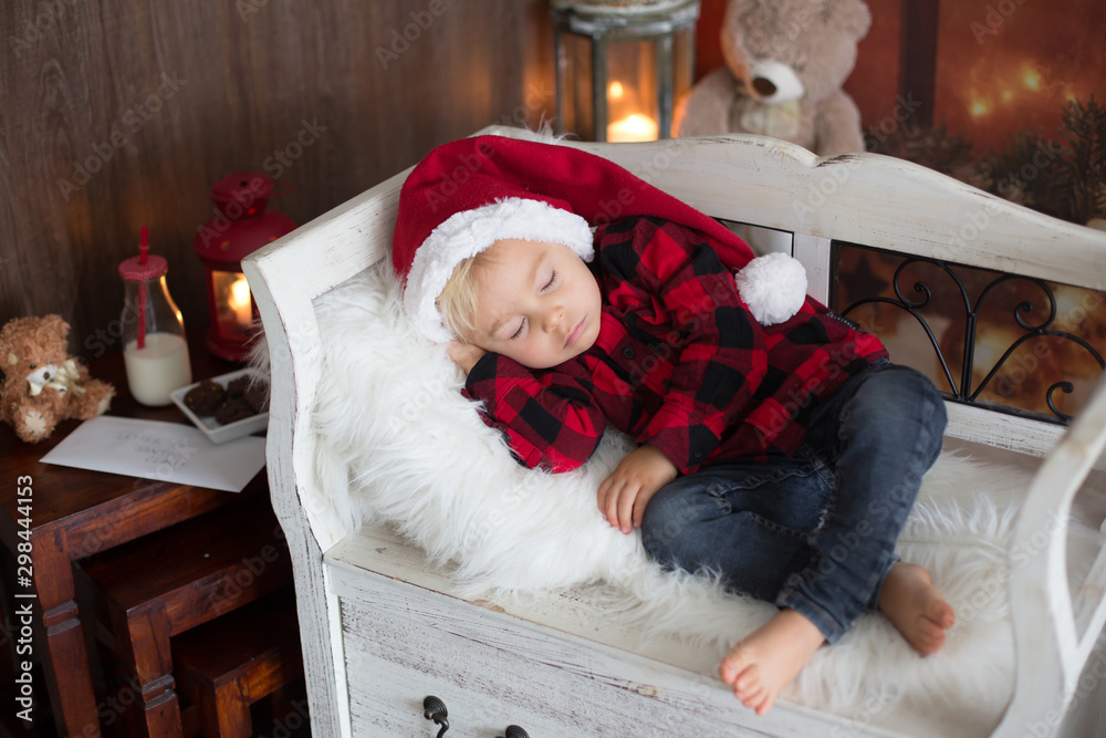 Obraz premium Sweet blonde toddler boy, sleeping with letter to Santa in hand, wishing present for the holidays
