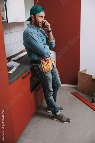Confident man talking on the phone during home repair