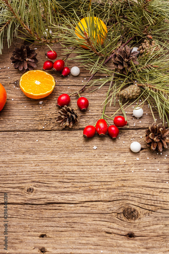 Spirit Christmas background. Fresh mandarins, dog-rose berries, candies, pine branches and cones, artificial snow