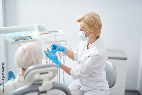 Dentist is showing false teeth for adult lady