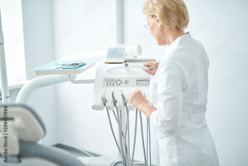 Professional dentist standing near the dental machine