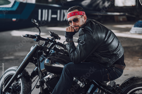 Bearded biker sitting on motorcycle in garage