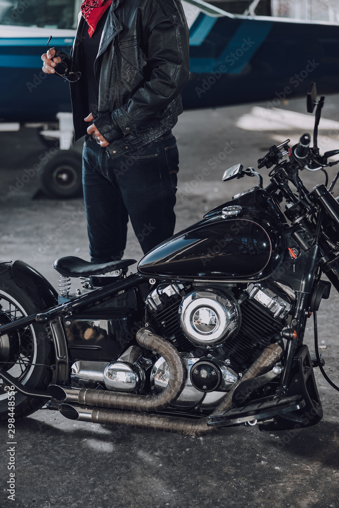 Cropped photo of man in leather clothes standing near motorcycle Cropped photo of man in leather clothes standing near motorcycle